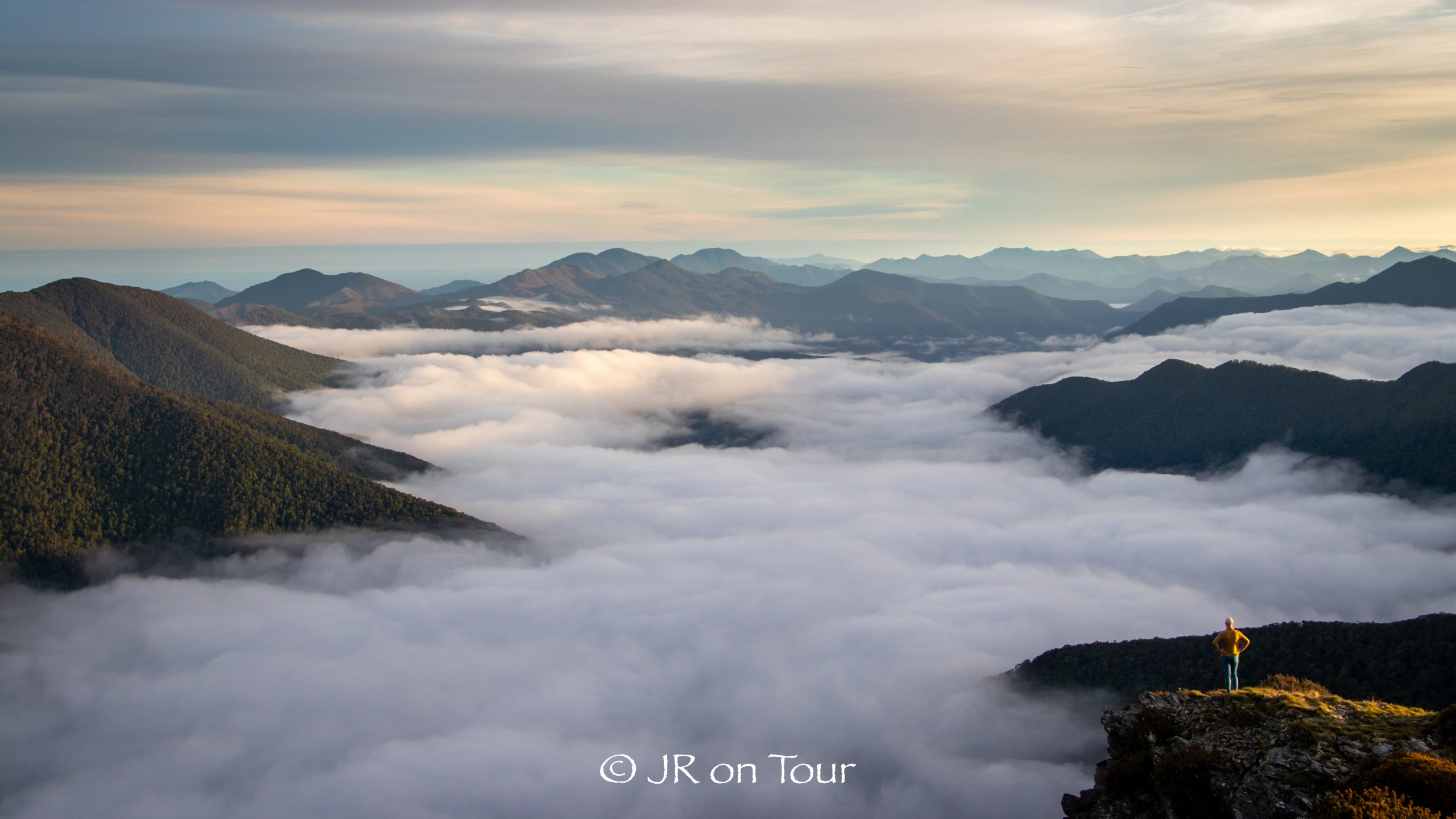 Jan steht auf einem Felsen oberhalb eines Wolkenmeers in den Richmond Ranges